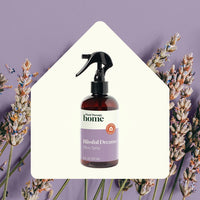 Bottle of 'Blissful Dreams' pillow spray surrounded by lavender flowers on a purple background