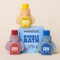 Honeysticks bubble bath bottles in various colors with a box on a beige background