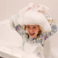 Child wearing a floral hooded towel with a white bathtub in the background