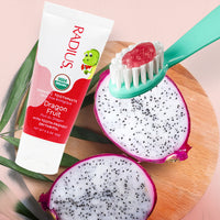 Radius Organic Dragon Fruit toothpaste with a toothbrush on dragon fruit halves against a pink background