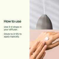 Hand applying a droplet of essential oil to wrist with diffuser in background