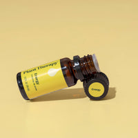 Brown essential oil bottle with yellow label on a beige background