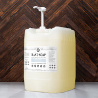Large container of body wash with a pump against a wooden background