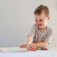 Child drawing with colorful crayons on a white surface