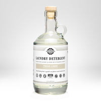 Glass bottle of laundry detergent with a wooden cap on a white background