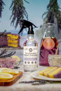 Bottle of all-purpose spray cleaner on a table with lavender and lemon slices in the background