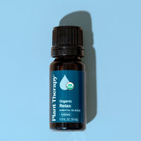 Essential oil bottle labeled 'Plant Therapy Organic Relax' on a light blue background