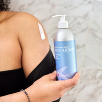 Person holding a bottle of body lotion with a blue label.