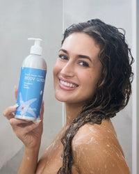 Woman holding a bottle of body wash in a bathroom setting