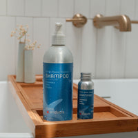 Two shampoo bottles on a wooden tray in a bathroom setting.