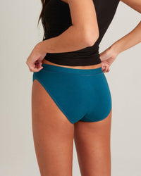 Person wearing teal high-waisted shorts and a black top on a neutral background