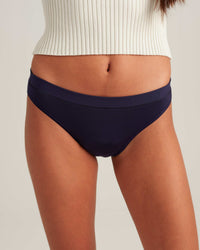 Navy blue bikini bottom worn by a person on a neutral background