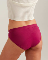 Person wearing bright pink high-waisted shorts with a white ribbed top on a light gray background