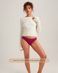 Woman wearing a white sweater and red underwear on a plain background