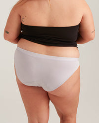 Person wearing a black bandeau top and light gray underwear on a plain background
