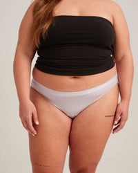 Person wearing a black strapless top and white bikini bottoms on a plain background