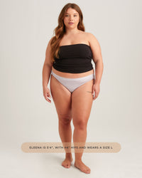 Woman wearing a black strapless top and gray underwear on a white background