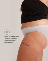 Person wearing light gray underwear with text about TENCEL material on a plain background