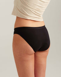 Person wearing black underwear with a plain background