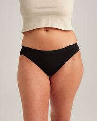 Person wearing black underwear on a plain background