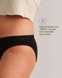 Person wearing black underwear with TENCEL label on a neutral background