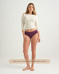 Woman wearing a white long-sleeve top and purple underwear on a white background