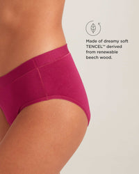 Close-up of a person wearing pink underwear with TENCEL branding on a light gray background.