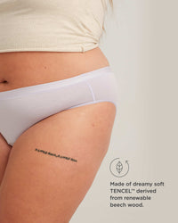Person wearing white underwear with a tattoo on their leg, on a plain background.