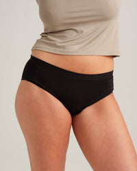 Person wearing black high-waisted bikini bottoms with a neutral background