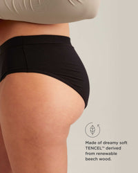 Person wearing black underwear with TENCEL label on a neutral background