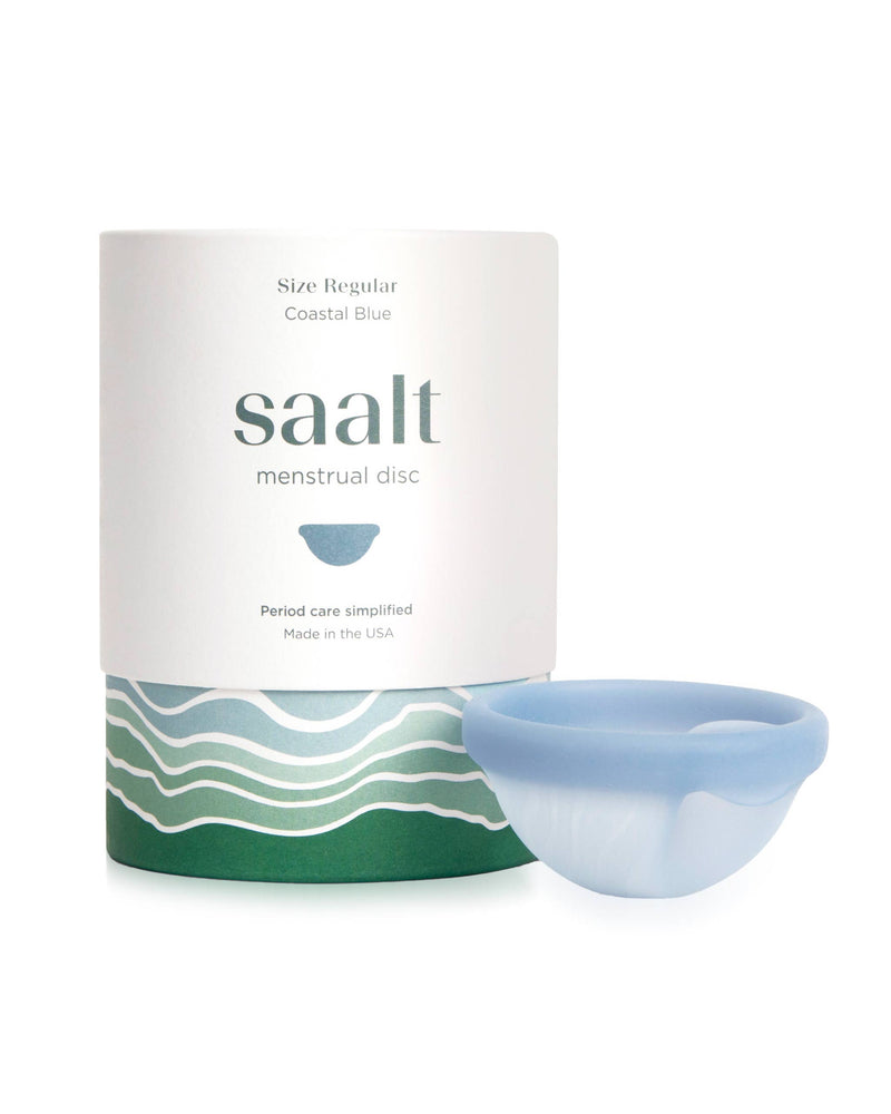 Saalt menstrual disc in Coastal Blue shown next to its white and green packaging container on a clean white background.