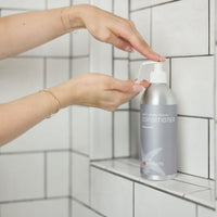 Person holding a bottle of Contariniex in a tiled shower area