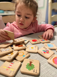 Child playing with educational wooden tiles at a table