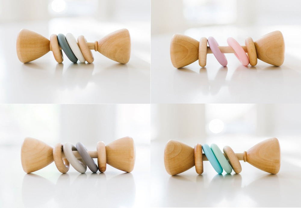 Four views of a wooden baby teething toy with colorful rings, displayed on a clean white background.