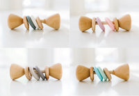 Four views of a wooden baby teething toy with colorful rings, displayed on a clean white background.