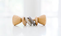 Wooden baby rattle with gray rings on a white background