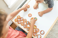 Children playing with cookie-shaped cards on a table