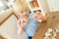 Child holding wooden tokens with icons on a wooden table